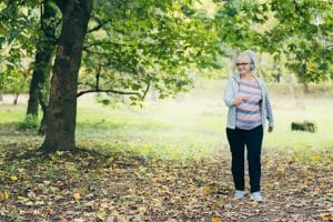 Beautiful woman, senior, running in headphones, walking in the park, playing sports